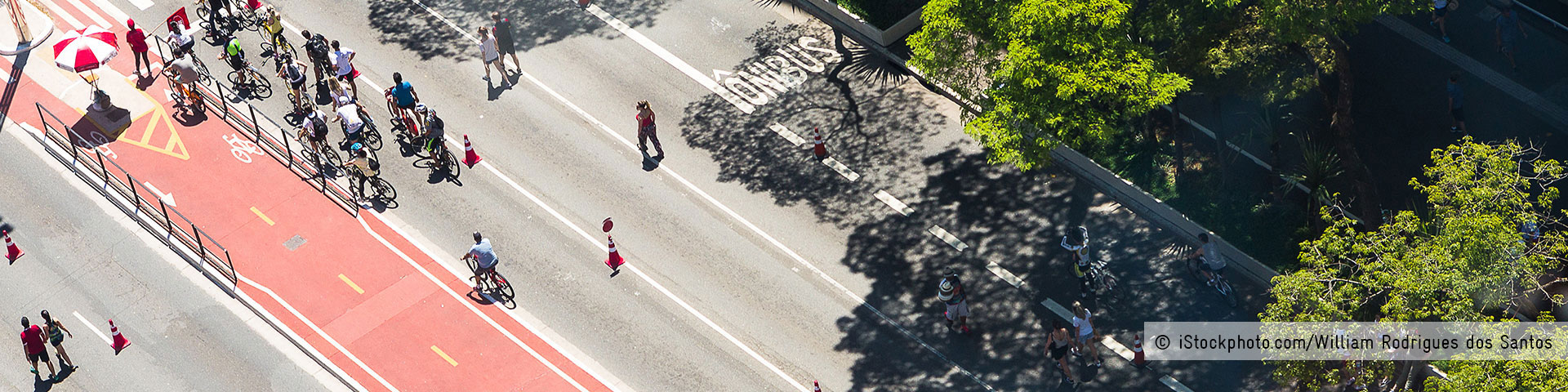 Blick von oben auf eine Straße mit rot markiertem Radweg, auf dem zahlreiche Menschen Fahrrad fahren. © iStockphoto.com/William Rodrigues dos Santos