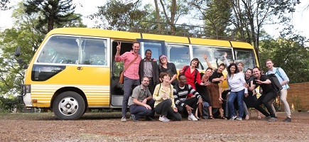 Eine Menschengruppe vor einem gelben Omnibus.