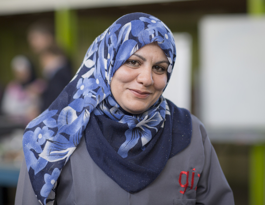 Eine syrische Geflüchtete in Hijab und GIZ-Uniform lächelt in die Kamera. Sie wird in einer jordanischen Berufsschule zur Klempnerin ausgebildet.