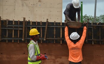 Bauarbeiter mit Schutzhelmen und Warnwesten bei der Arbeit auf einer Baustelle.
