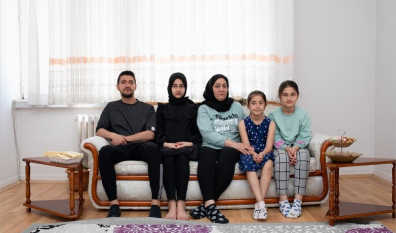 Ein Familienfoto zeigt eine Mutter mit vier Kindern auf einem Sofa. 