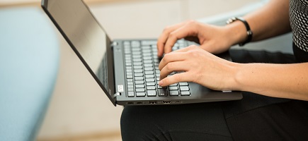 Hände arbeiten an der Tastatur eines Laptops.