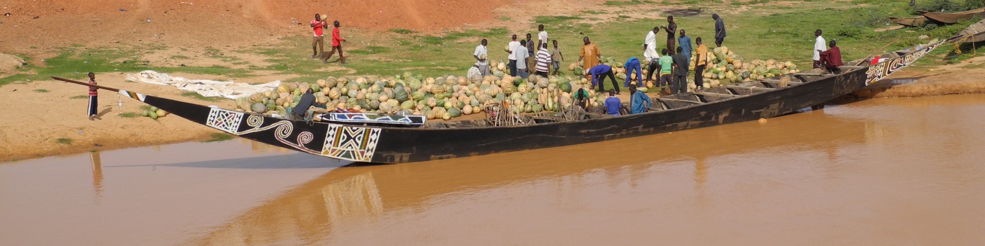 Menschen entladen ein Holzschiff mit Kürbissen in Niger.