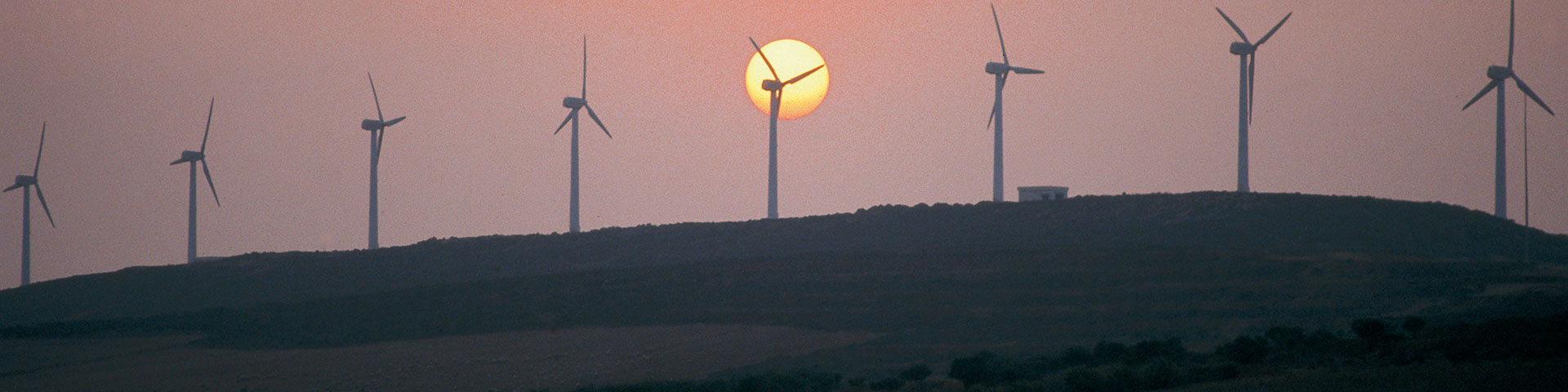 Windkraftanlagen auf einem Hügel während eines Sonnenuntergangs.