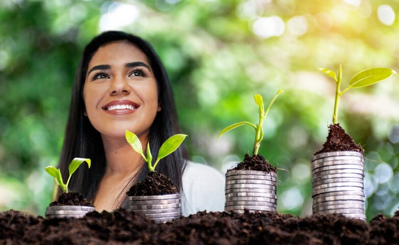 Frau seht hinter Pflanzen, die eine grüne wirtschaftliche Erholung symbolisieren