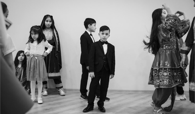 Ein Schwarzweißfoto zeigt eine Gruppe von Kindern, die zusammen tanzt und spielt. 