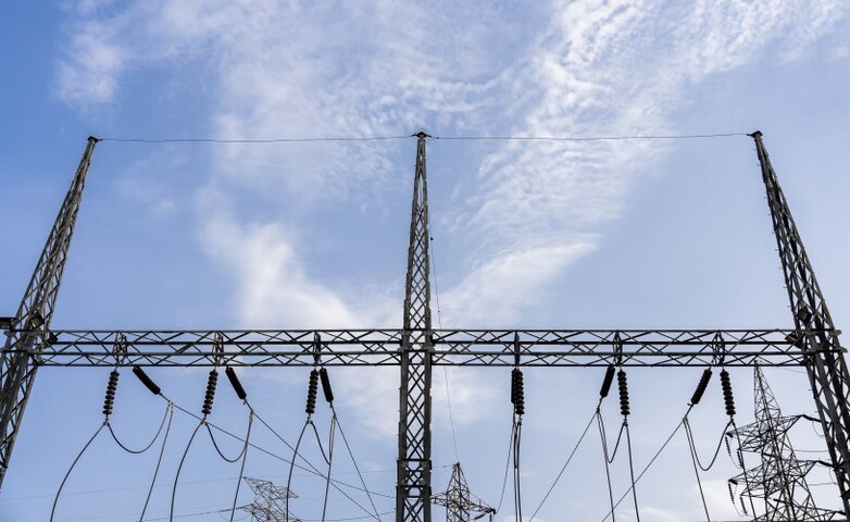 High-voltage power lines and electricity pylons stretch across the landscape, transmitting electricity across distances.