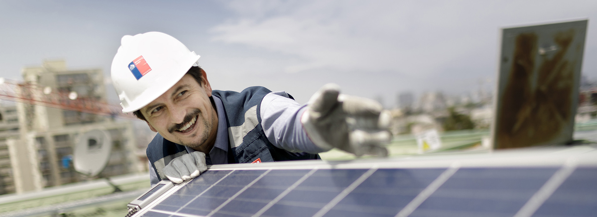 Ein Mann in Arbeitsausrüstung an einem Solarpanel.