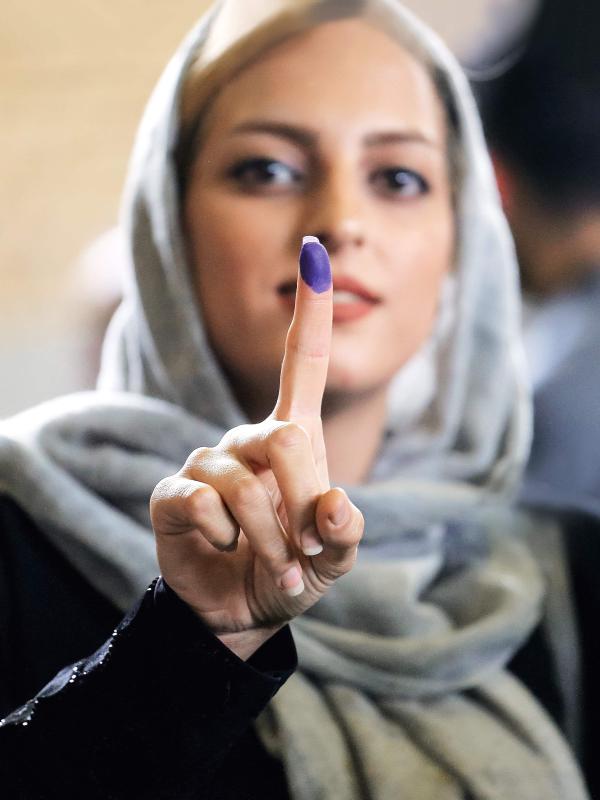 Eine junge Frau mit Kopftuch hält ihren Zeigefinger mit einer violett farbenen Fingerkuppe in die Kamera