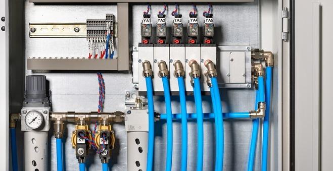 Nahaufnahme einer industriellen Maschine mit silbernen Rohrleitungen, Ventilen und metallischen Komponenten.