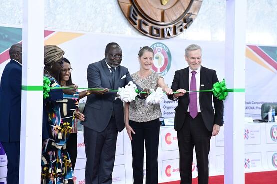 Personen schneiden gemeinsam ein grünes Band durch