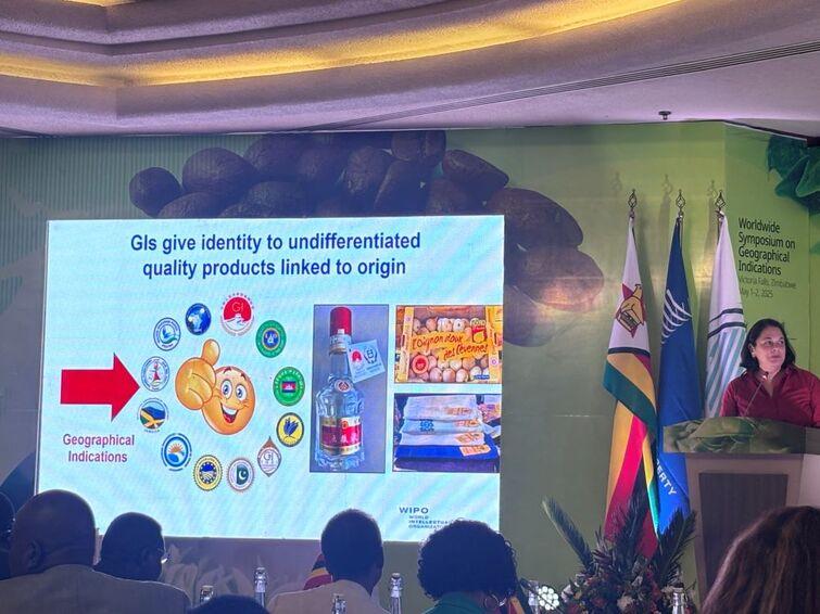 People sitting at tables listening to a woman give a speech. Picture in the background saying "GIs give identity to undifferentiated quality products linked to origin"