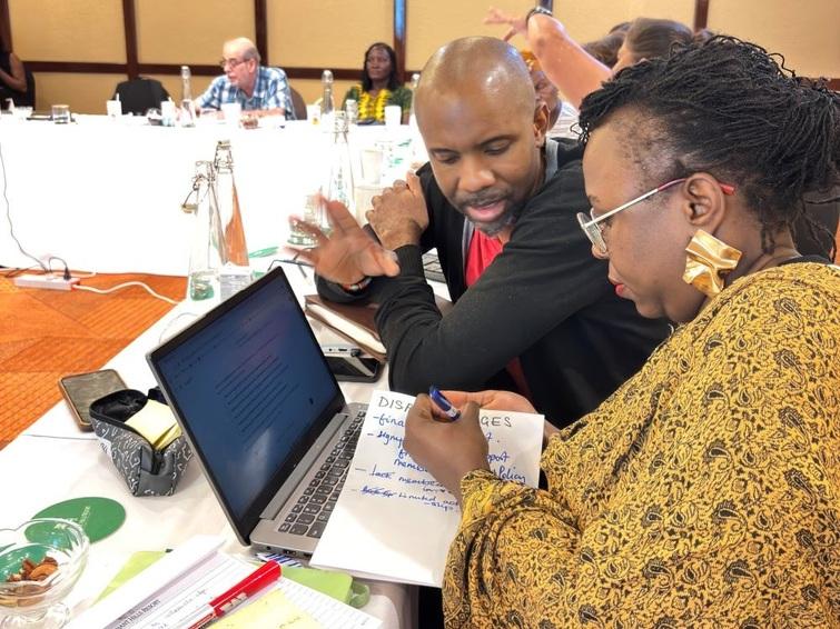 Man speaking to a woman that is writing something on a paper