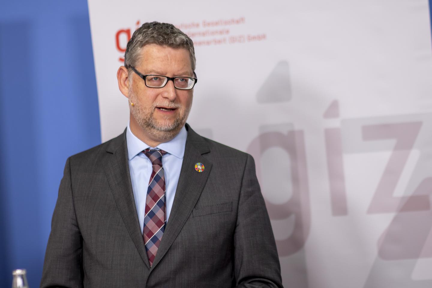 Thorsten Schäfer-Gümbel during a speech in front of a GIZ banner.