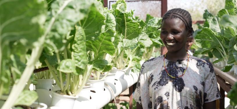 A woman is attending to plants in a greenhouse.