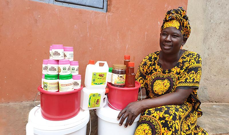A woman sits next to containers with agricultural products