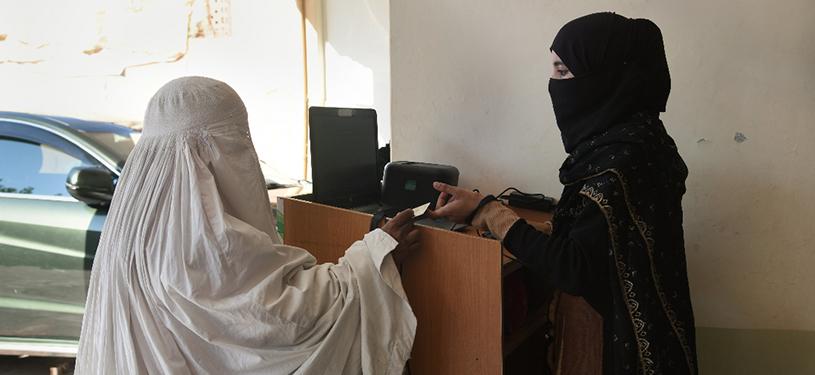 Two women in burkas at a counter
