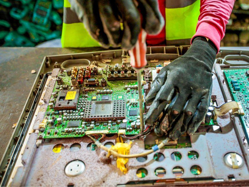 Old circuit boards are unscrewed from a housing.
