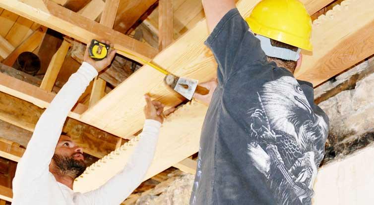 Carpenters survey the wooden ceiling.