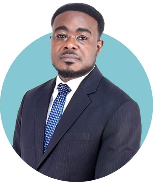 A man in a dark suit and blue and white patterned tie poses in front of a light blue circular background.