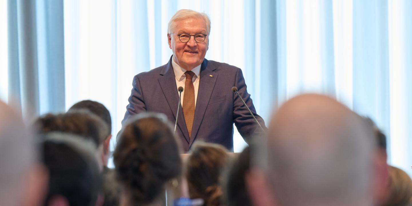 Federal President Frank-Walter Steinmeier giving a speech in front of the GIZ employees, who are seen from behind.