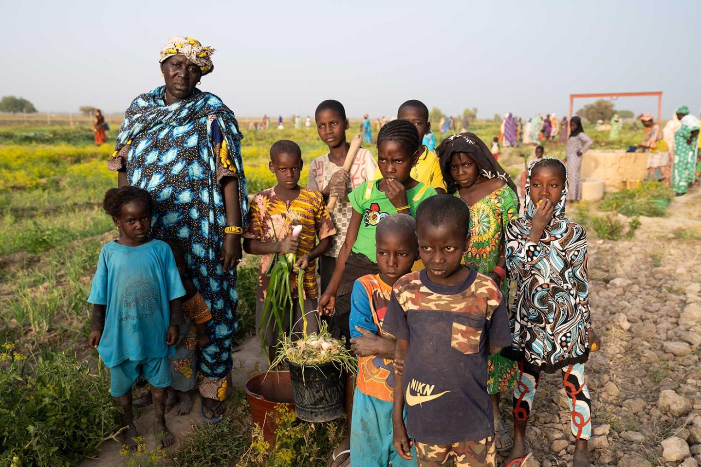 Eine Frau und eine Gruppe von Kindern an einem Feldrand