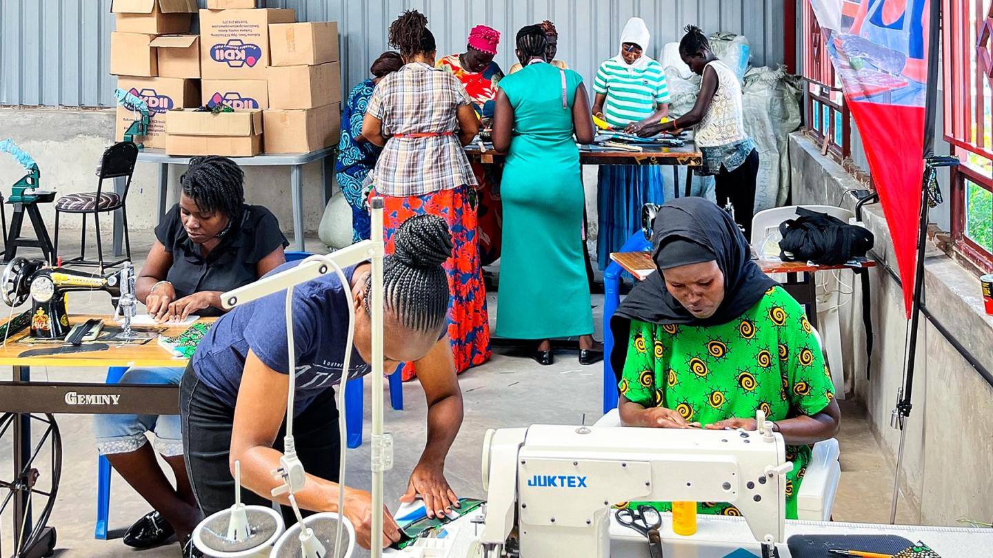 A group of women in a factory hall practise handling recycling materials and use them to sew products.