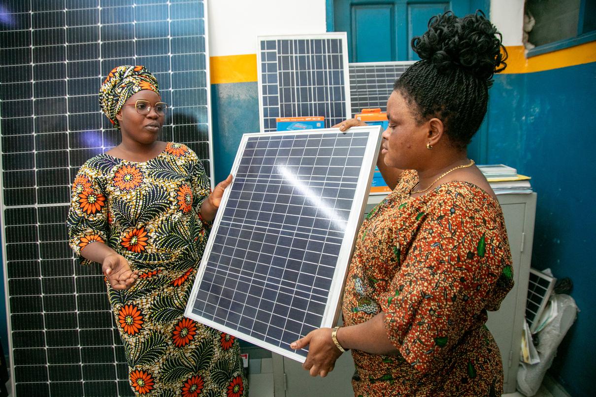 Two women present a solar panel.