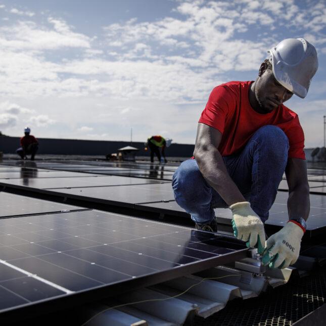 Ein Arbeiter bringt ein Solarpanel auf einem Dach an