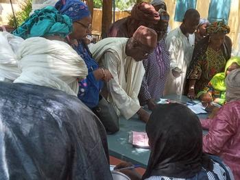 A group of people stand outdoors around a table.