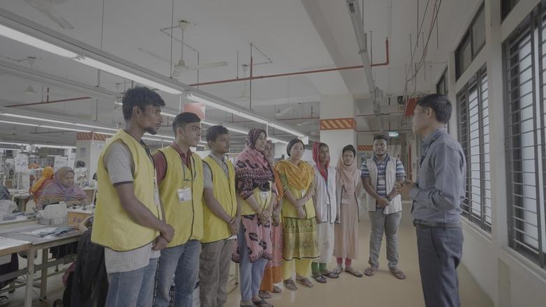 A man talks with textile factory workers. (Photo: GIZ/Yousuf Khan)