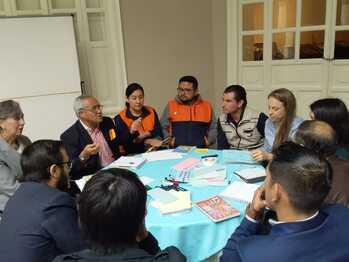 Eine Personengruppe sitzt an einem runden Tisch.