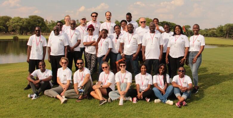 Eine Gruppe von Menschen posiert in einem grünen Park für ein Foto.