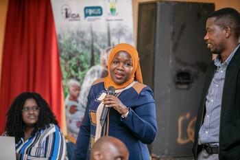 Eine Frau mit Kopftuch spricht in ein Mikrofon.