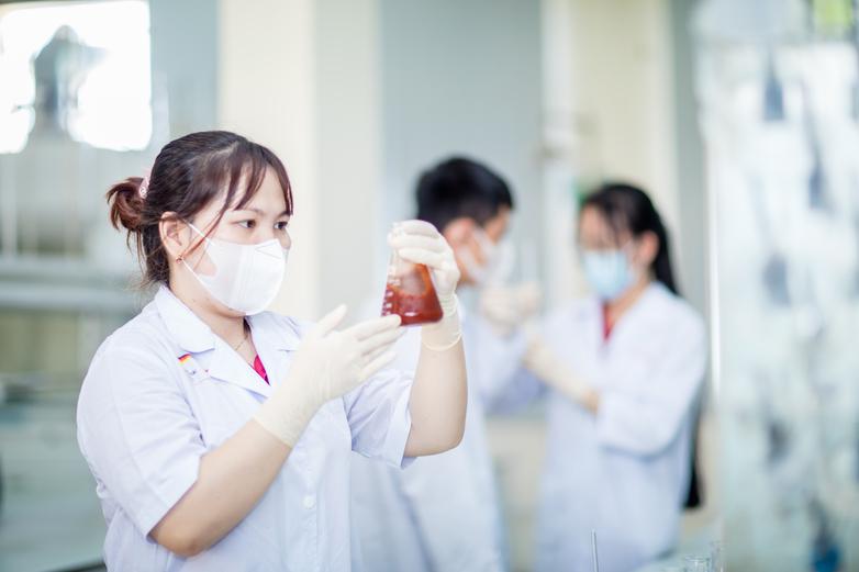 A woman in a laboratory looks at treated wastewater in a container.
