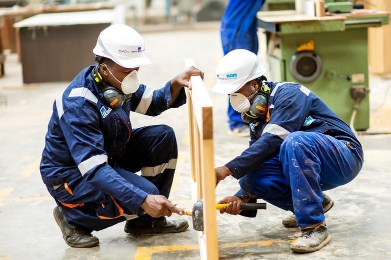Two people in protective clothing building a wooden frame for a door.