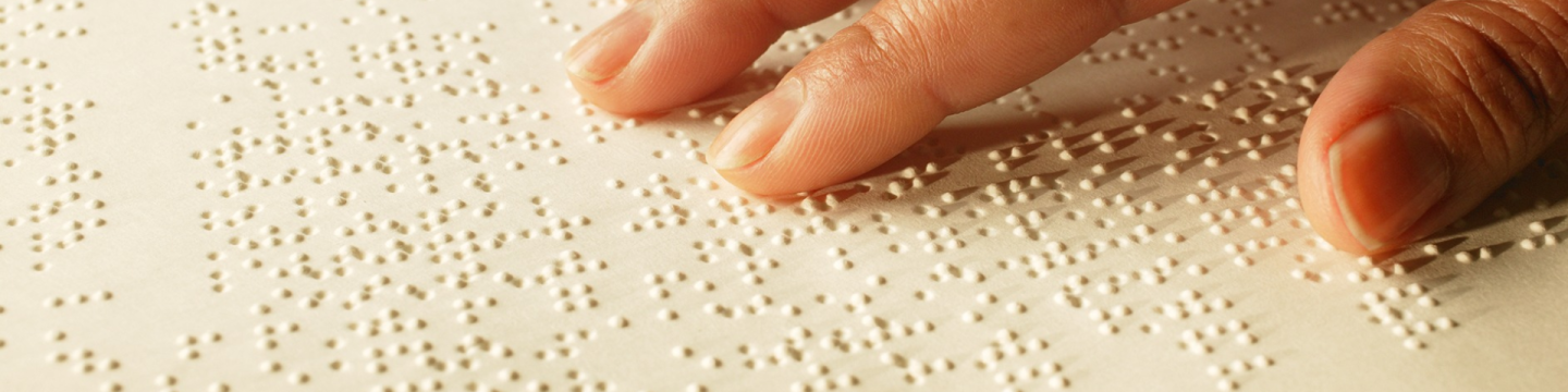 Eine Hand liest Braille-Schrift.