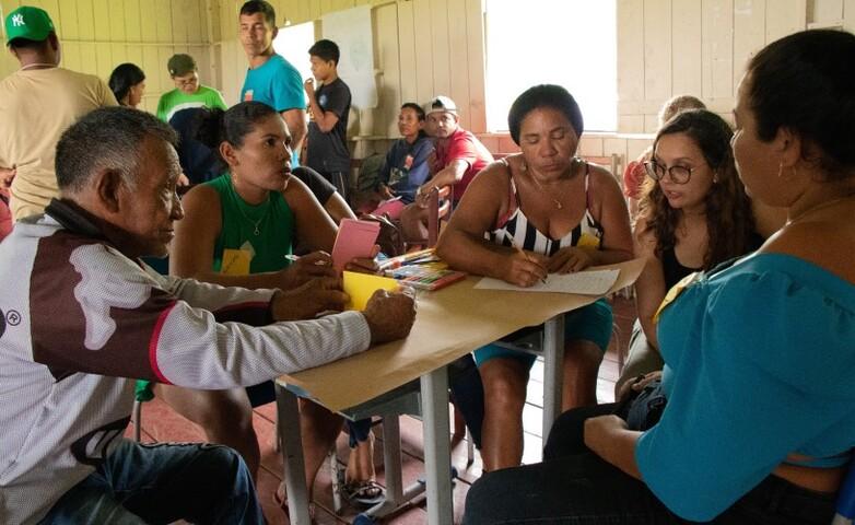 Community members gathered around a table during a meeting in a rural area, discussing eco-friendly forest management.