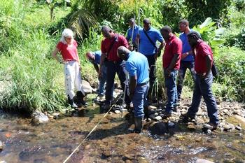 Employees of the national water authority stand on the bank of a river and measure the water flow. © GIZ Grenada/Garwin Walters