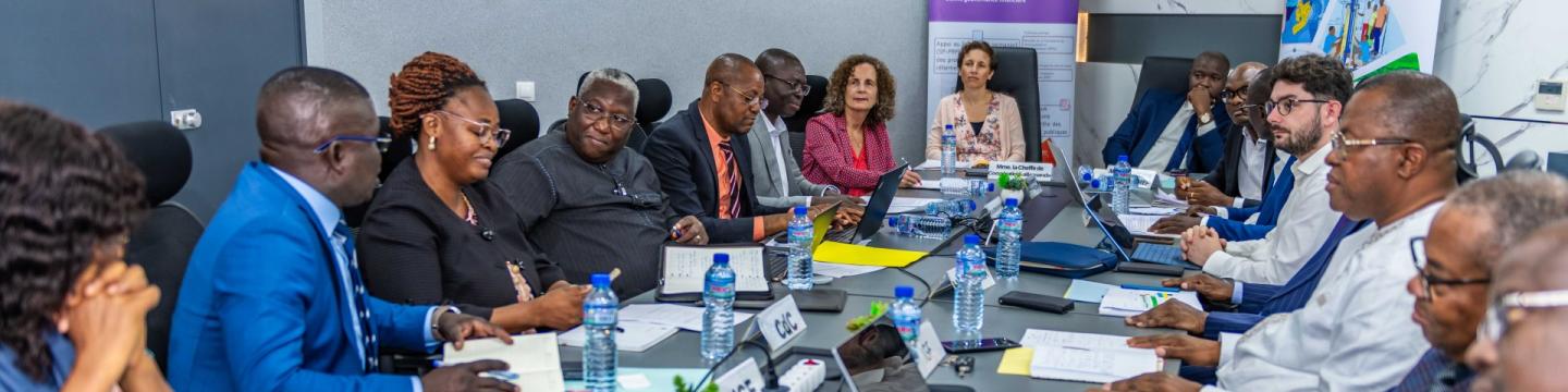 15 Personen sitzen an einem langen Tisch und besprechen sich.