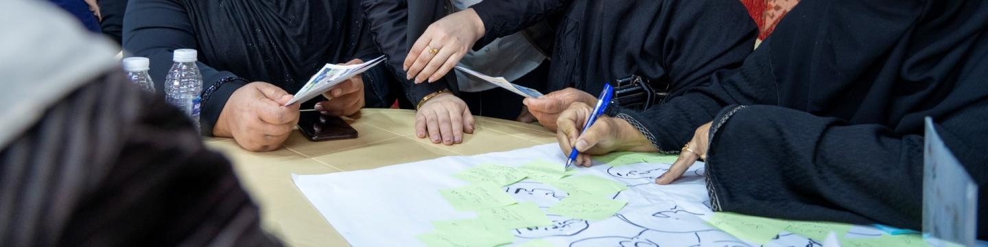 Frauen beschriften ein Plakat im Rahmen einer Schulung zur Klimawandelanpassung der Landwirtschaft.