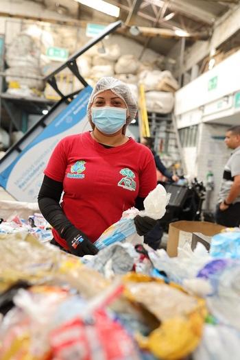 A woman wearing protective clothing is sorting waste packaging.