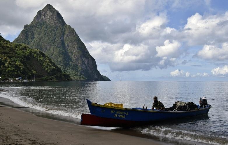 A fisherman beaches a blue wooden boat.