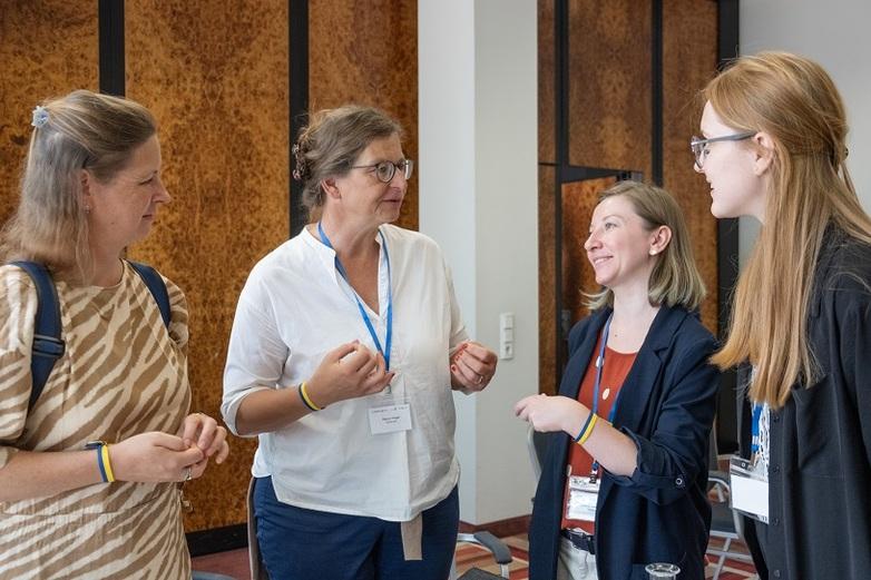 Vier Frauen stehen im Halbkreis zusammen und diskutieren miteinander.