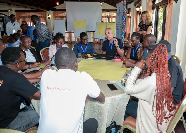 Teilnehmende eines Workshops sitzen an einem Tisch zusammen während des Blue Economy Innovation and Investment Summit in Mombasa, Kenia.