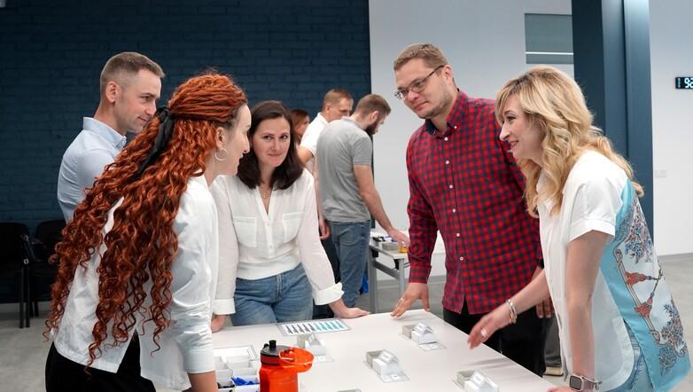 Ukrainian entrepreneurs stand around a table during a discussion in a training session.