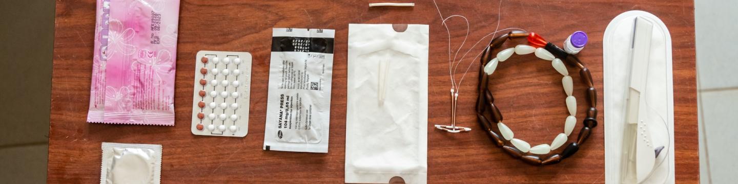 Verschiedene Verhütungsmittel liegen auf einem Holztisch.