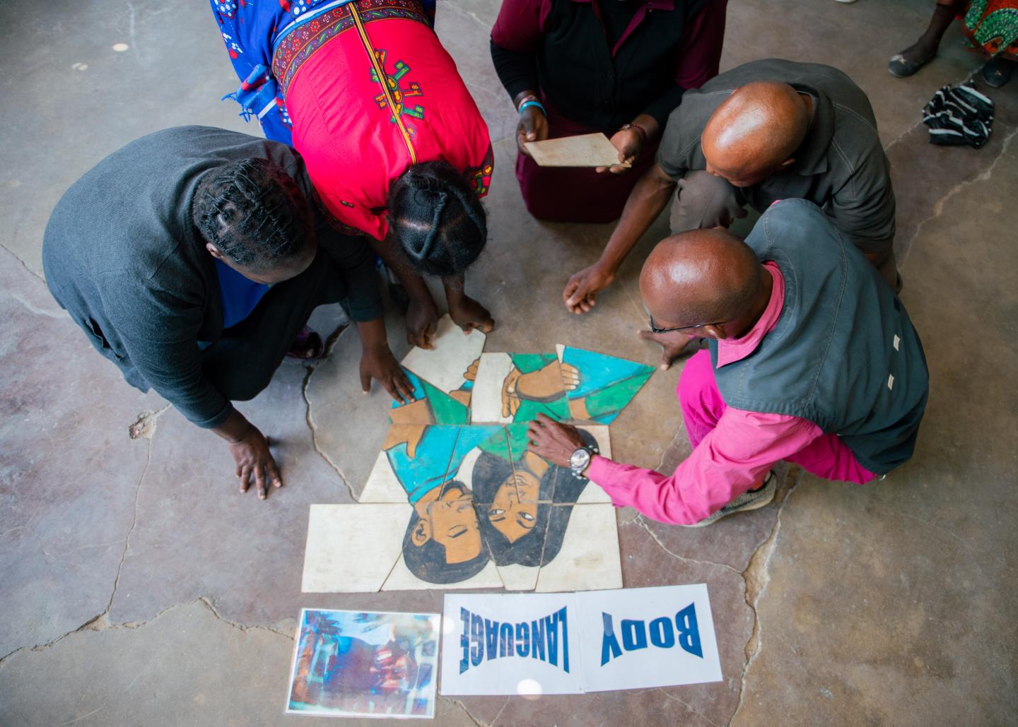 Parents sit together and do a puzzle at a multi-activity event on AIDS, love and sexuality.