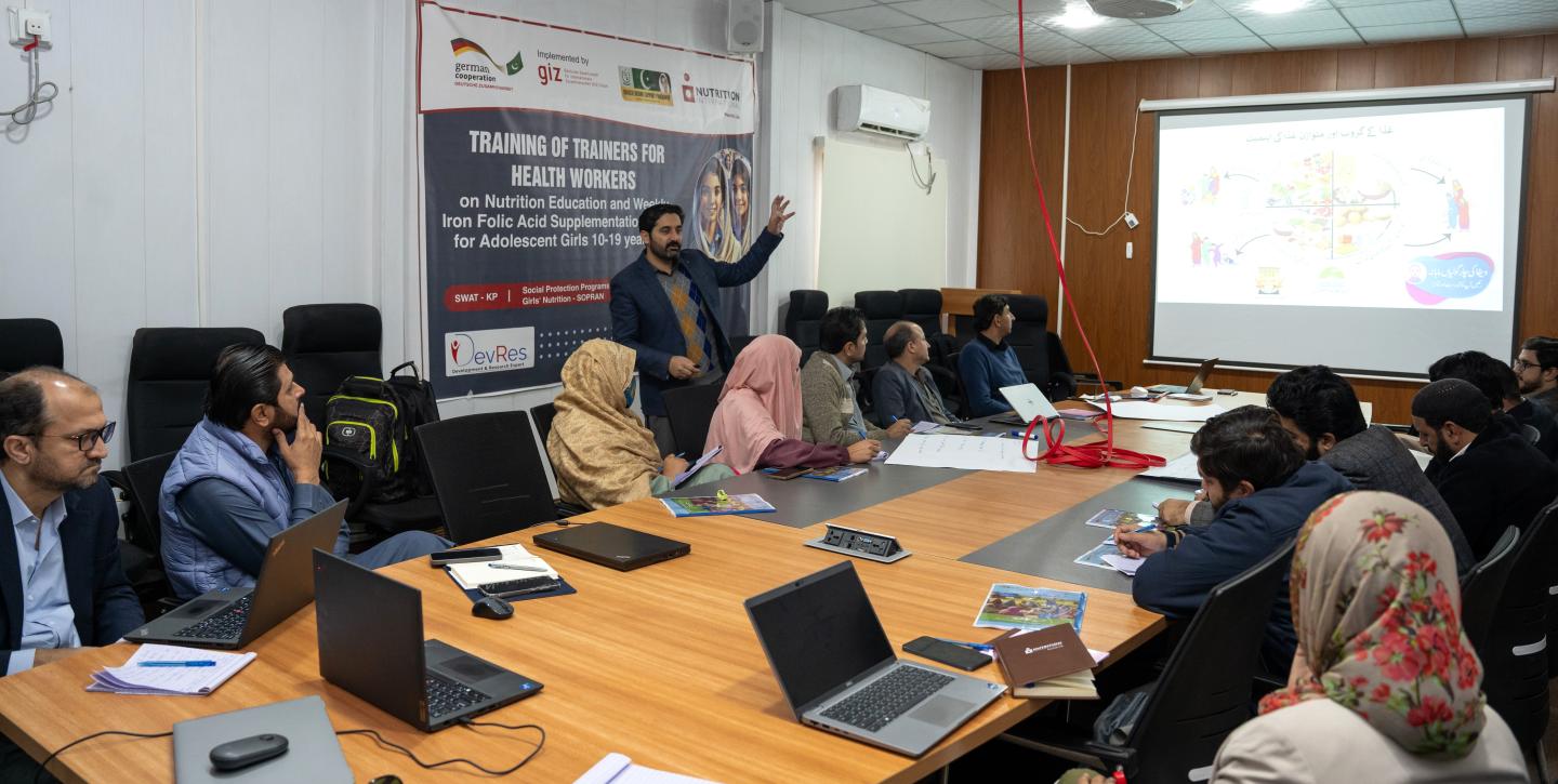 Mehrere Menschen sitzen an einem Tisch, arbeiten an Laptops und tauschen Ideen aus.
