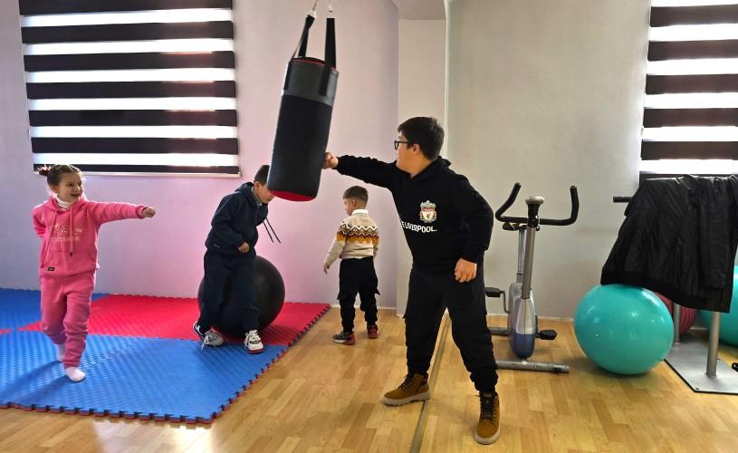 Children with disabilities practice coordination and mobility exercises using a punching bag in a rehabilitation centre.